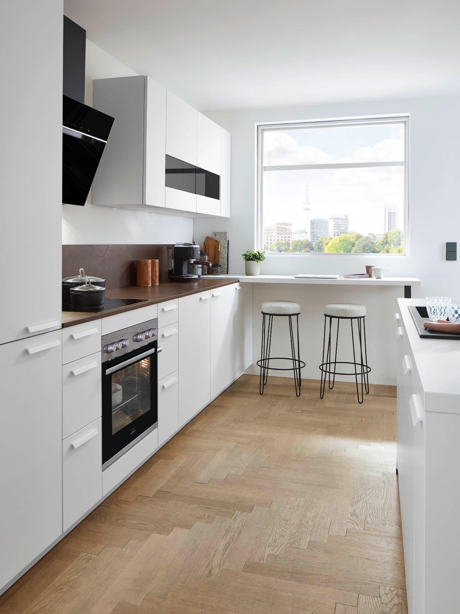 Světlá podlaha, bílý nábytek a lesklé povrchy v malé kuchyni skvěle fungují.